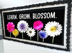 a sign that says learn grow blossom on the side of a wall with flowers painted on it