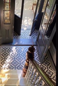 the stairs lead up to an entryway with stained glass doors and decorative flooring