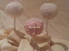 two pink cake pops with white sprinkles on them sitting on a cloth