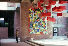 a man standing in front of a large painting on the side of a brick building