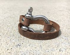 Strap on some style with our Leather Shackle Wrap Bracelet. This unique accessory adds a touch of edgy elegance to any outfit, perfect for those who are both playful and fashion-forward. Wraps around the wrist for a secure fit, making it both stylish and functional. Stainless steel shackle accentuated with brown leather. A great everyday accessory that can be dressed up or dressed down. Adjustable Metal Bracelets With Leather Strap, Adjustable Metal Bracelet With Leather Strap, Adjustable Metal Bracelets For Everyday, Trendy Leather Jewelry As Fashion Accessory, Casual Leather Jewelry For Everyday, Adjustable Trendy Leather Bracelet, Trendy Leather Strap Jewelry, Trendy Adjustable Leather Cuff Bracelet, Casual Everyday Jewelry With Leather Strap