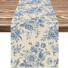 a blue and white floral table runner on top of a wooden table with wood planks