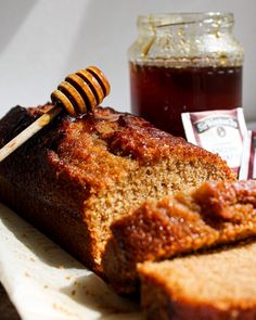 a loaf of bread with honey on top and a jar of jam in the background