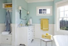 a bathroom with blue walls and yellow towels on the bathtub next to a window