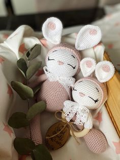 two crocheted stuffed animals sitting on top of a bed next to a plant