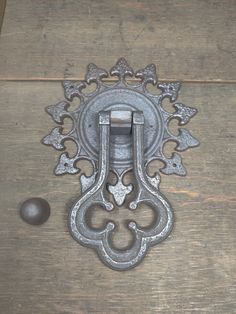 an old metal door handle on top of a wooden table next to a ball and screwdriver