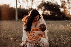 a woman holding a baby in a field