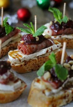 small appetizers are arranged on bread with toothpicks and garnishes