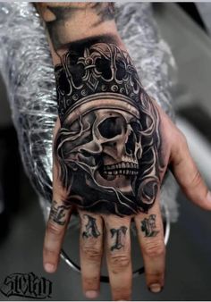 a man's hand with a skull and crown tattoo on it