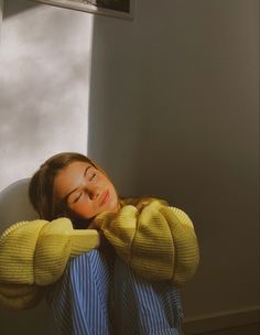 a woman is sitting in a chair with her eyes closed and hands on her head