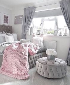 a bed room with a neatly made bed and a round ottoman next to the window