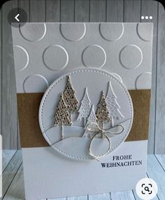 a white card with two trees and a bow on the front that says frohe weihnachten