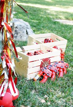 a wooden crate filled with red fire extinguishers on top of green grass