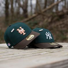 two new york mets hats sitting on top of a wooden table in front of trees