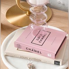 a stack of books sitting on top of a white plate next to a candle holder