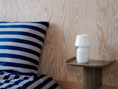 a white vase sitting on top of a wooden table next to a blue and white pillow