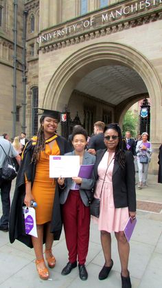 three women standing in front of a building with a sign that says university of manchester