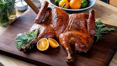 a large piece of meat sitting on top of a wooden cutting board next to oranges