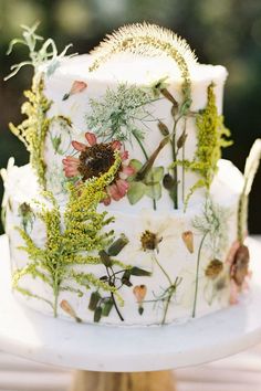 a white cake with flowers and plants on it