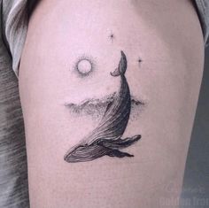 a woman's thigh with a whale tattoo on it