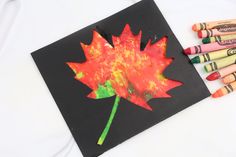 an art project with crayons and colored crayons next to a leaf