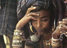 a woman is looking at her cellphone while wearing bracelets and headgear