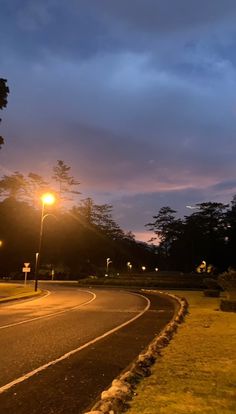 an empty street at night with the lights on and trees in the backround