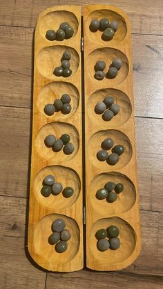 two wooden spoons filled with olives on top of a wood table next to each other