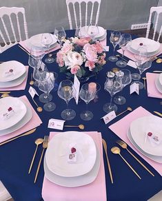 the table is set with pink and white plates, silverware, and napkins