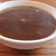 a white bowl filled with soup on top of a wooden table