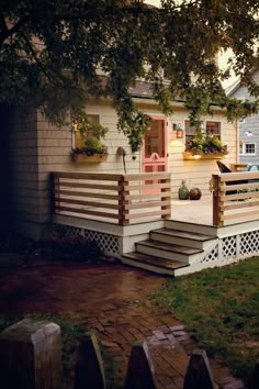 a white house with steps leading up to the front door and side porch, next to a tree