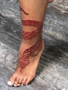 a woman's foot with a red snake tattoo on the side of her leg