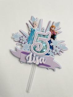 there is a cake topper with the number five and frozen princesses on it