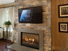 a living room with a stone fireplace and flat screen tv mounted above the fire place