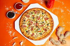 a pizza sitting on top of an orange table next to some condiments and sauce