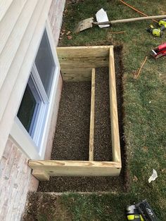 a wooden box sitting in the grass next to a window