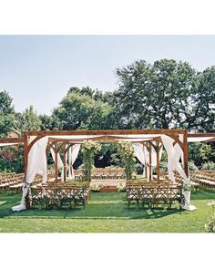 an outdoor wedding setup with white draping and wooden chairs