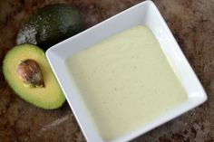 an avocado sitting next to a bowl of dressing