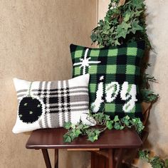 two green and white pillows sitting on top of a wooden table next to a plant