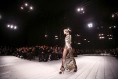 a model walks down the catwalk in front of an audience at a fashion show