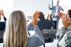 business people applauding each other in front of a projector screen stock photo