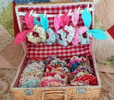 an open suitcase filled with lots of fabric and bows on clothes pins attached to the handle