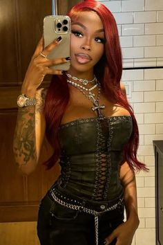 a woman with red hair taking a selfie in a mirror wearing a corset