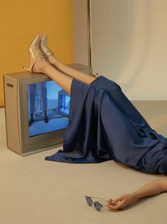 a woman laying on the floor in front of a tv with her legs up and feet down