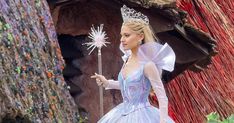 a woman in a blue dress and tiara standing next to a fake snowflake