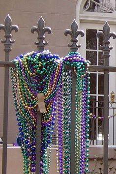 a bunch of beads that are hanging on a fence next to a building with a door in the background