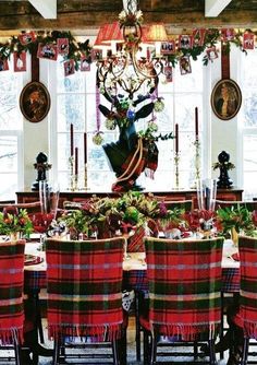 a dining room table with plaid chairs and christmas decorations on the wall above it is decorated with deer heads