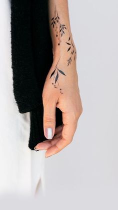 a woman's hand with a small tattoo on her left wrist and the other arm