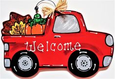 a red truck with a welcome sign in the back is decorated with pumpkins and gourds