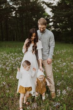 a man, woman and child are standing in the grass